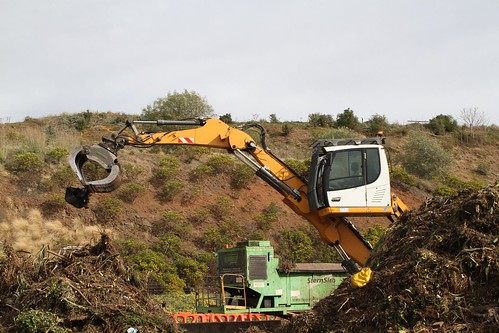 Liebherr LH 22 material handling machine picks out a piece of broken wheelie bin out of the incoming organic waste