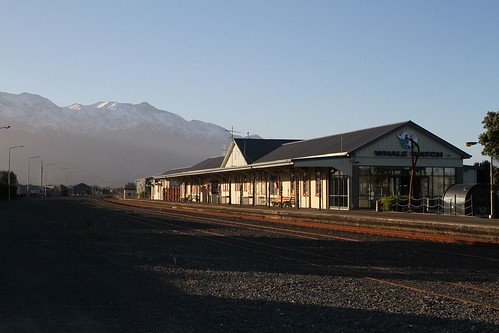 Snow covered peaks of the Kaikōura Ranges tower above the beachside railway station at Kaikōura