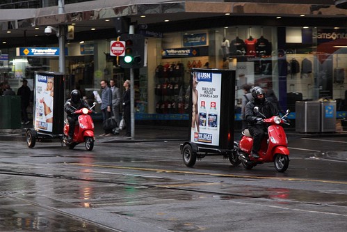 Motor scooters towing advertising billboards