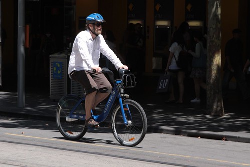 Tourist heads up Swanston Street with their hired bike and helmet