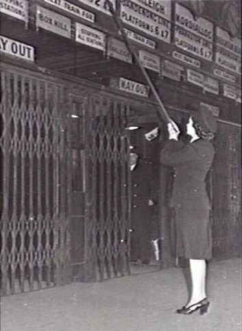 Australian War Memorial image #126587 - Miss Peace Harber, one of the first women railway employees, changing the indicator clocks at the Degraves Street entrance of Flinders Street Station.