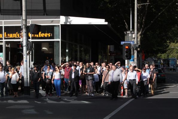 Pack of commuters waiting at the Collins Street Street traffic lights to cross Spencer Street