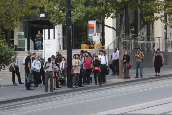 Crowds of passengers wait outside Southern Cross Station for the next bus to Port Melbourne