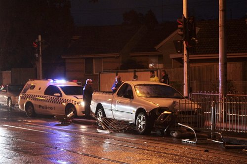 Police in attendance, looking over the ute impaled on five metres of tram safety zone fence