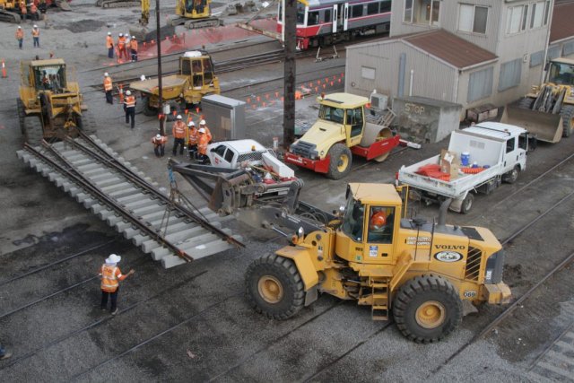 Moving a track panel from the staging area with a pair of front end loaders