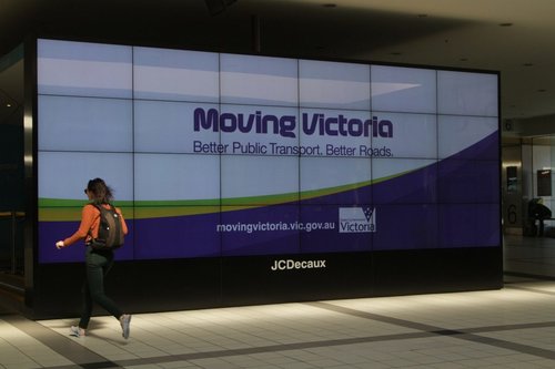 'Moving Victoria' propaganda among the advertisements on the big screen at Flinders Street Station