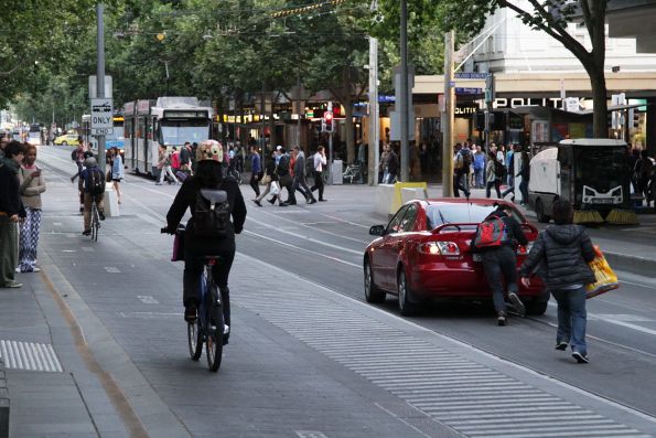 Passersby push a broken down car out of the tram stop on Swanston Street