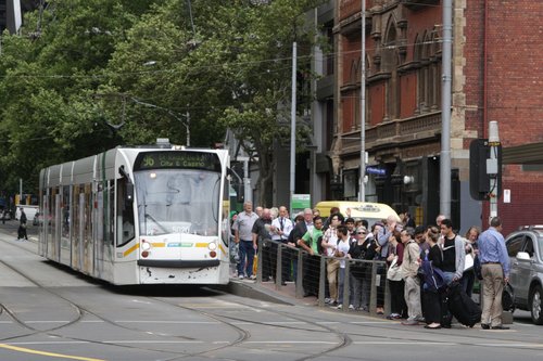 Tram load of passengers depart a route 96 service at the corner of Bourke and Spencer Streets