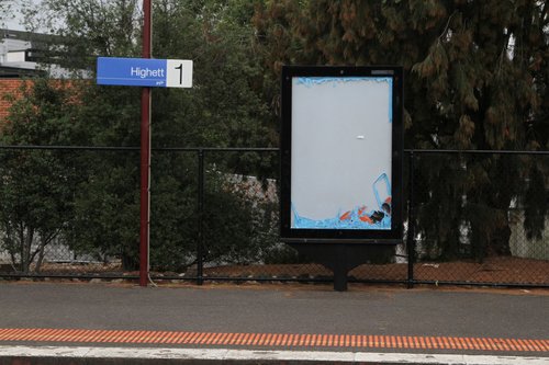 Tattered PTV advertisement inside a JCDecaux billboard at Highett station