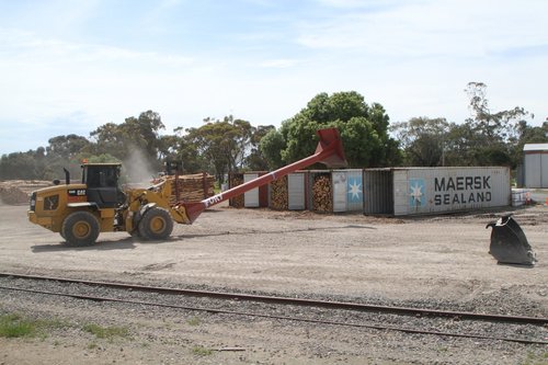 Loader ready to push another pile of logs into a container