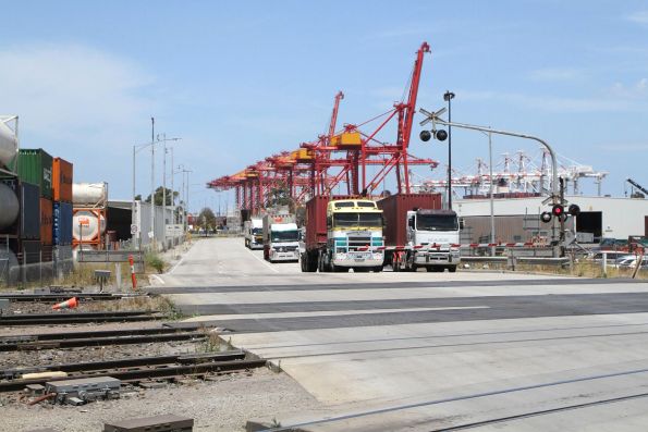 Container trucks waiting for a passing train at the Dock Link Road level crossing