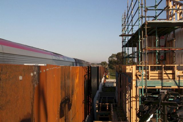 Three storey townhouse development peeks over the noise walls on the new elevated track