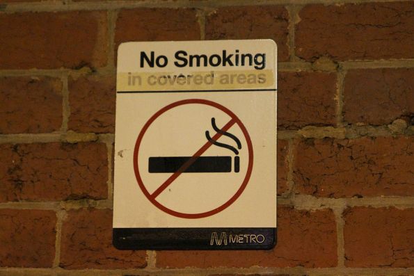 No Smoking sign with the covered over 'in covered areas' section started to become uncovered