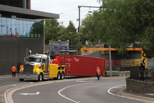 Heavy tow truck drags the 40 foot container clear of the bridge