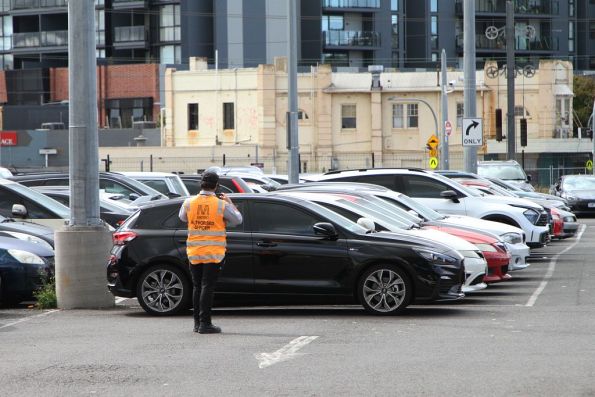 Authorised Officers ticketing cars parked in no standing zones at a railway station car park